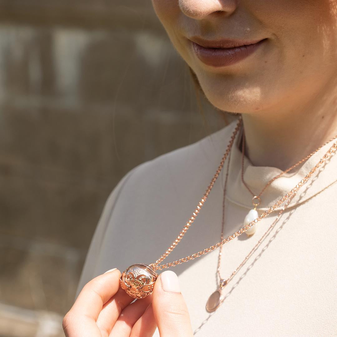 model in white top holding rose gold memory keeper locket