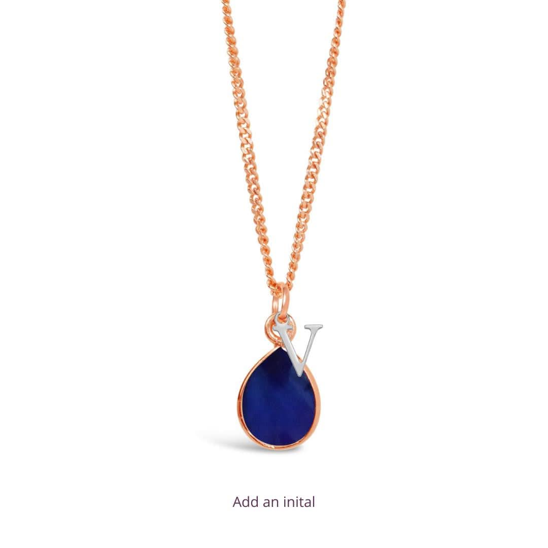 rose gold charm necklace with silver initial charm on a white background