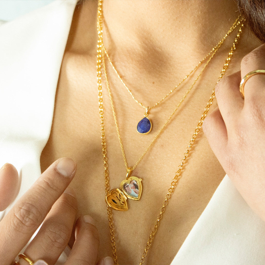 model wearing sapphire heart locket in gold revealing inside