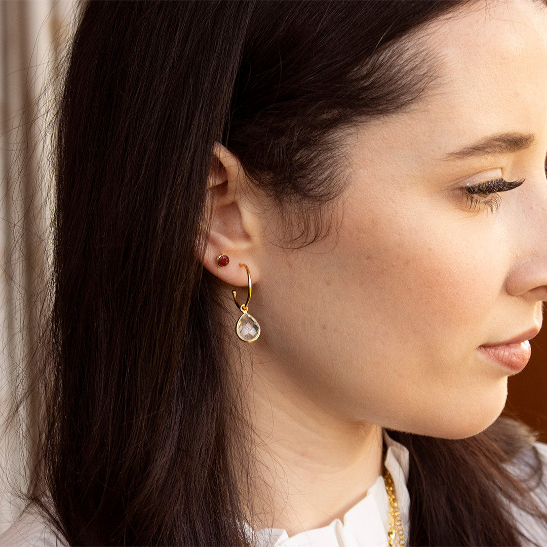 model wearing ruby mini stud earrings paired with white quartz drop hoop earrings 