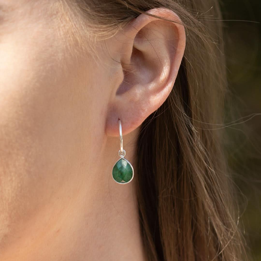 closeup of model wearing emerald drop hoop earrings in silver