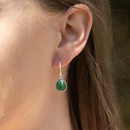 closeup of model wearing emerald drop hoop earrings in silver