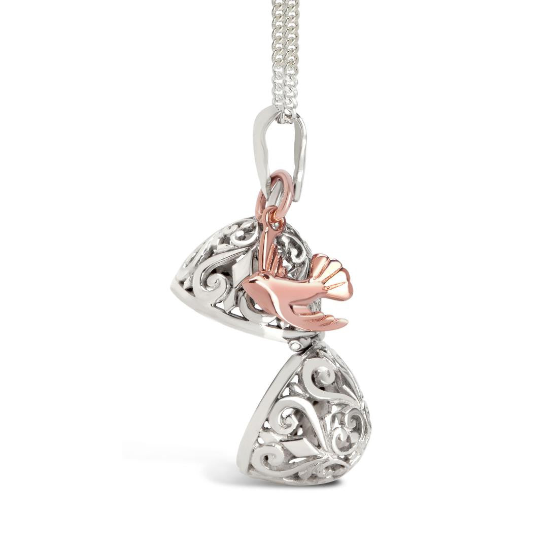 opened bird locket in silver with rose gold bird charm on a white background