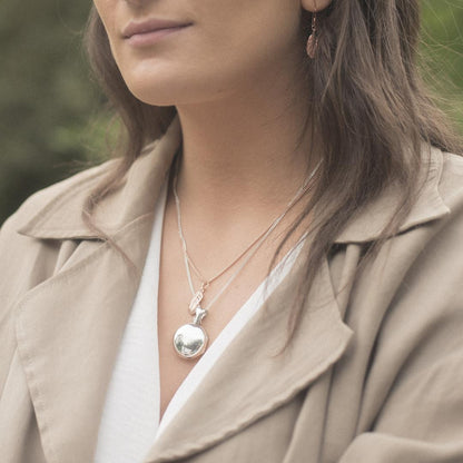 model wearing feather locket in white gold with feather charm