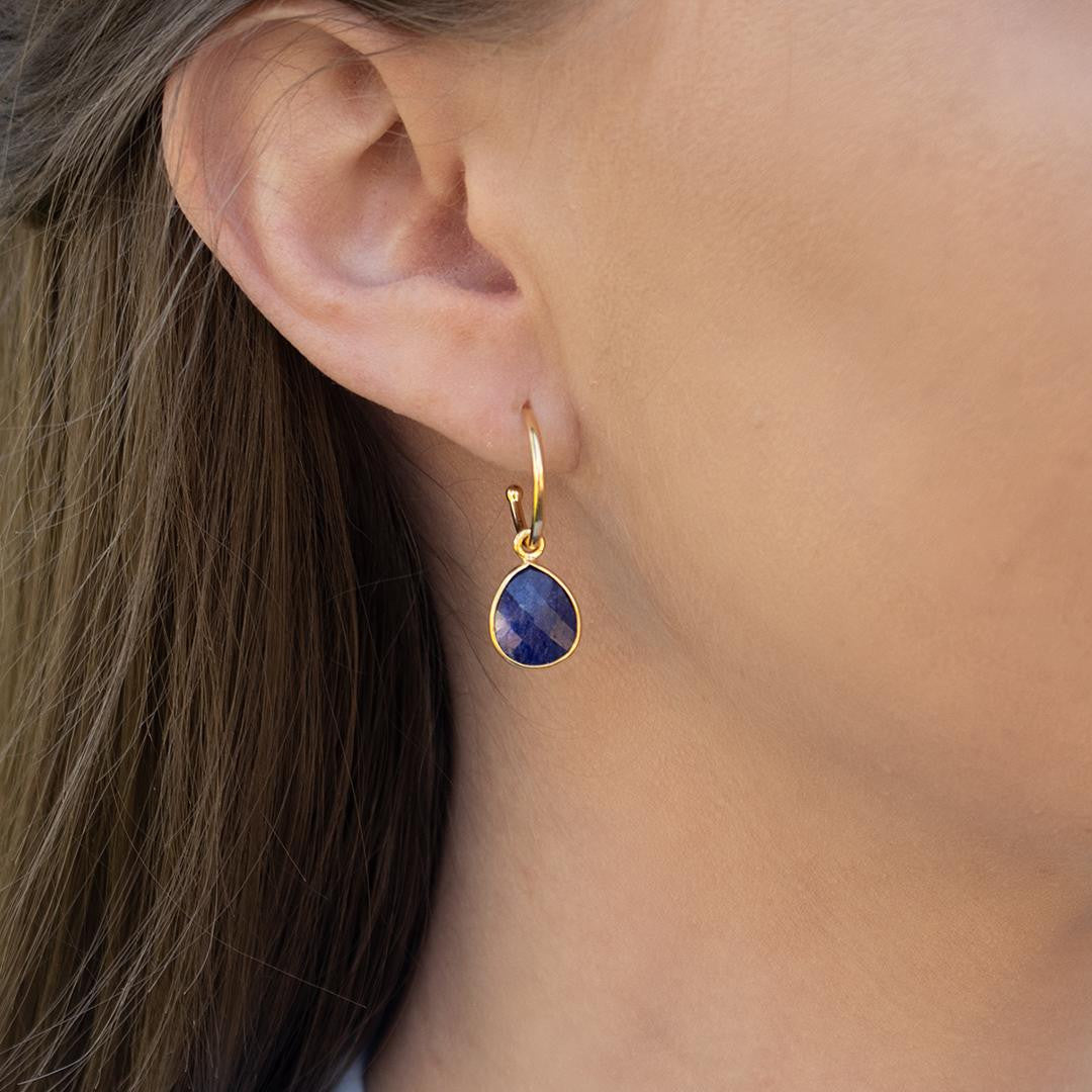 model wearing sapphire drop hoop earrings in gold