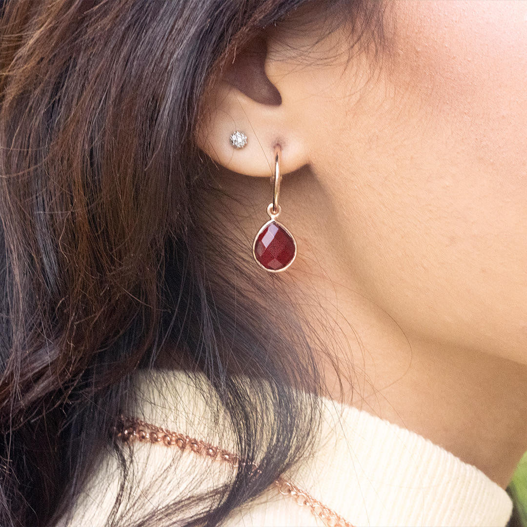 model wearing rose gold earrings with garnet gem stone