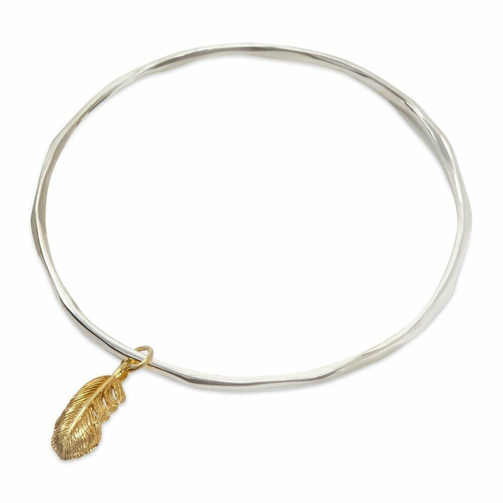 silver bangle with gold feather charm on a white background