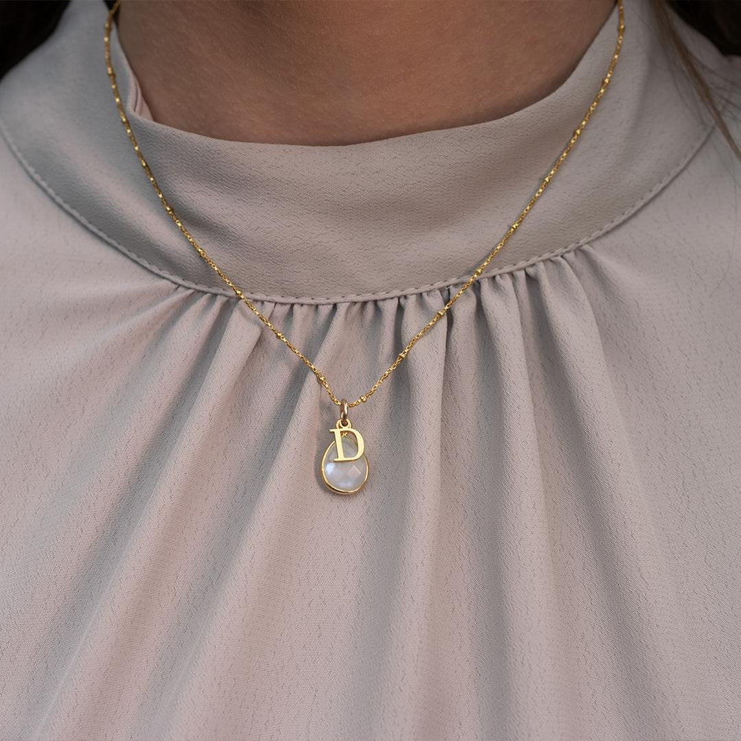 model wearing moonstone charm necklace with gold initial charm