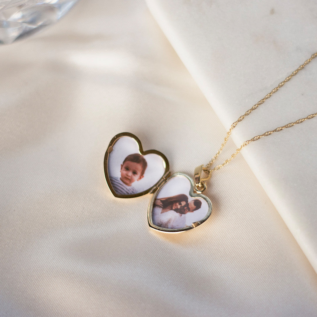 opened diamond heart locket in gold with family photos inside