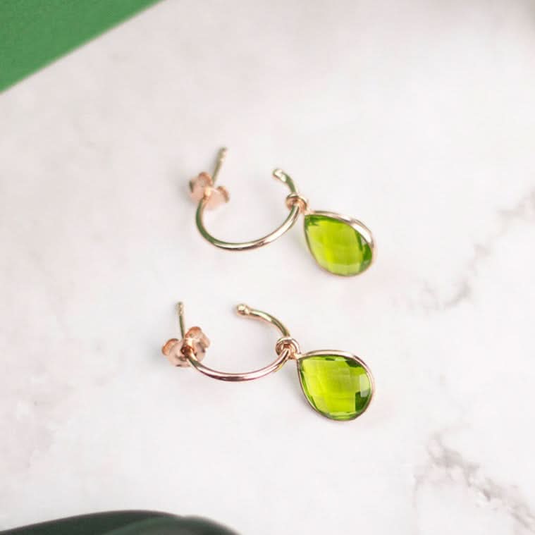 peridot drop hoop earrings in rose gold on a marble table