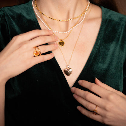closeup of model wearing diamond heart locket in gold
