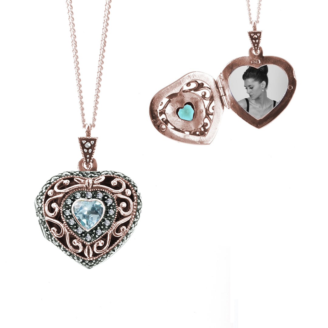 Heart shaped rose gold locket with blue topaz gemstone in centre and locket open showing photos