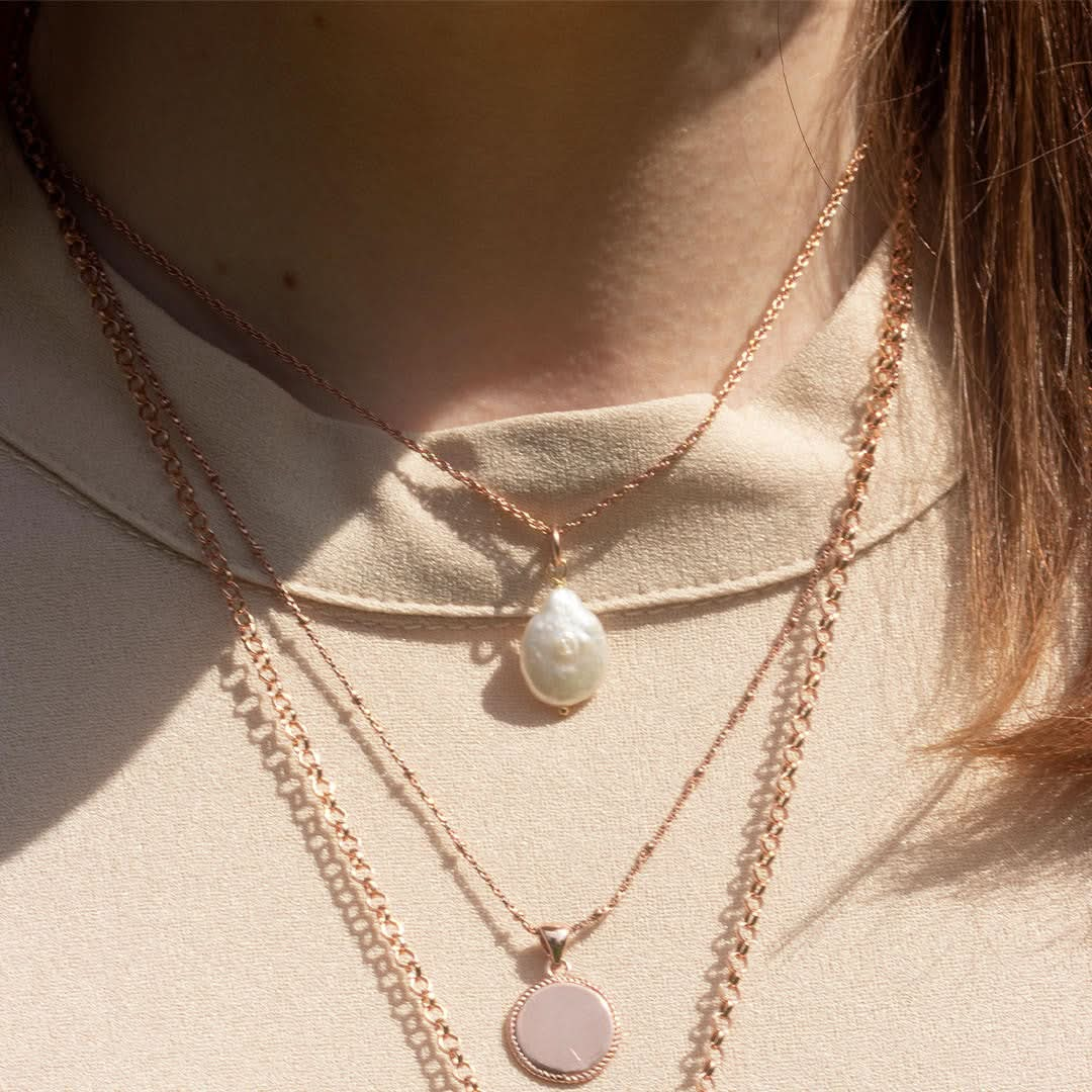 closeup of model wearing rope chain with baroque pearl