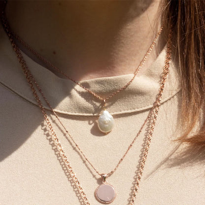 closeup of model wearing rope chain with baroque pearl