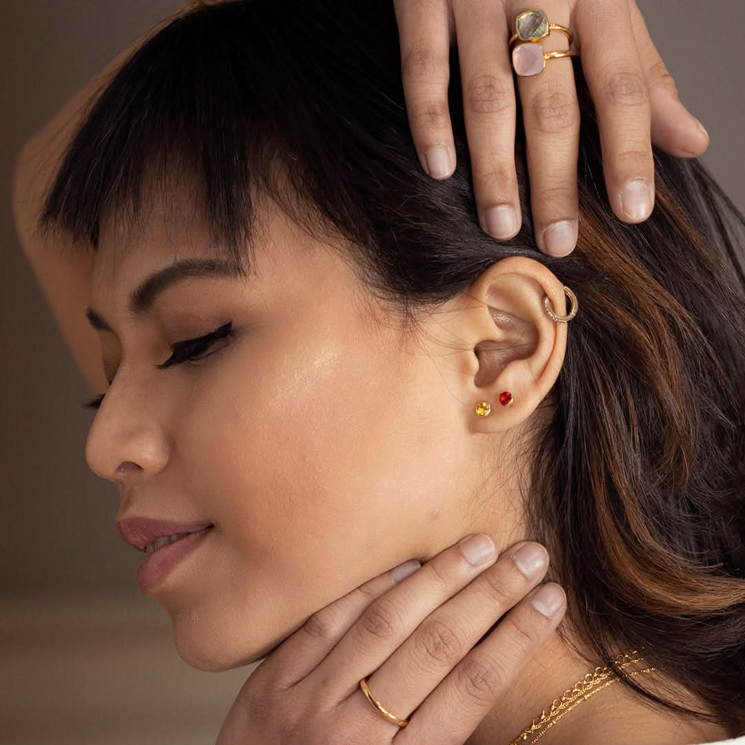 Model wearing garnet mini stud earrings in rose gold