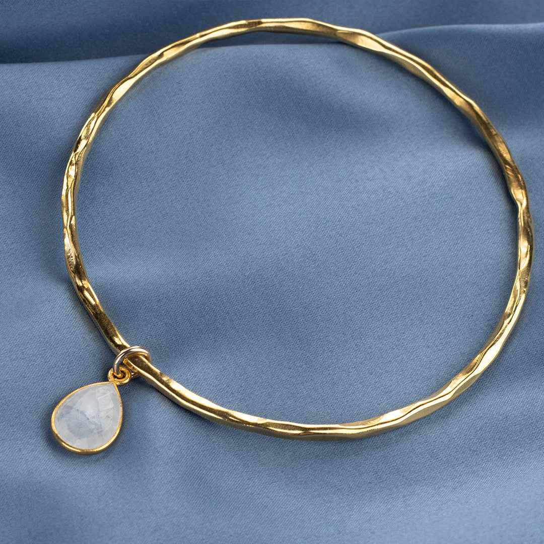 gold moonstone charm bangle on a piece of blue fabric