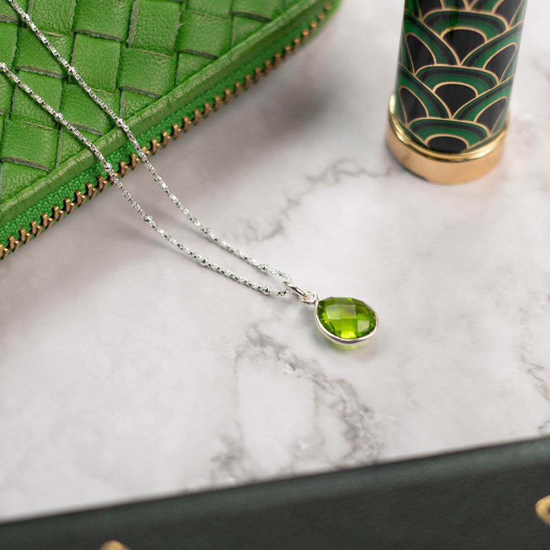 genuine green peridot silver  pendant necklace on silver chain on marble background