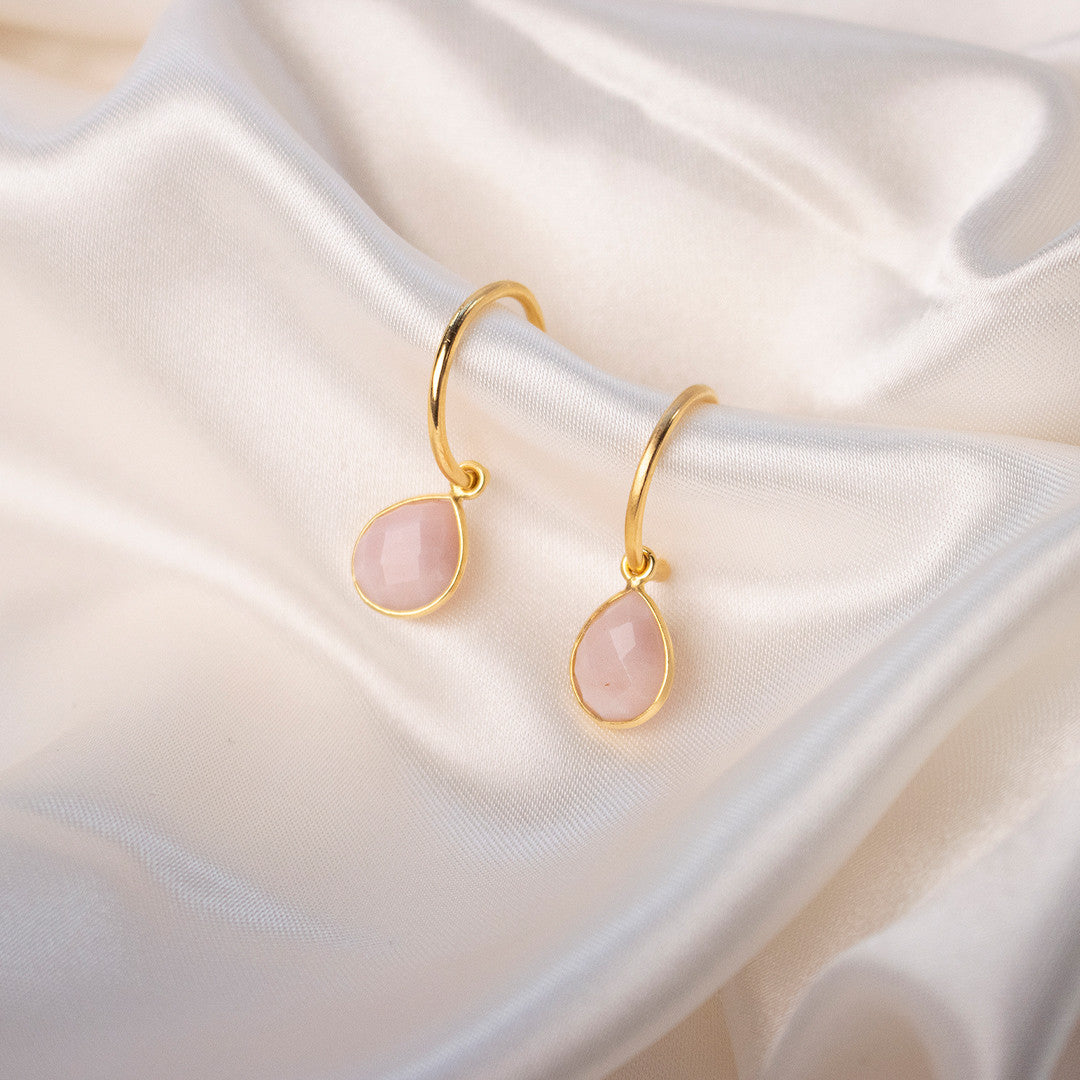 pink opal drop hoop earrings in gold on piece of white fabric