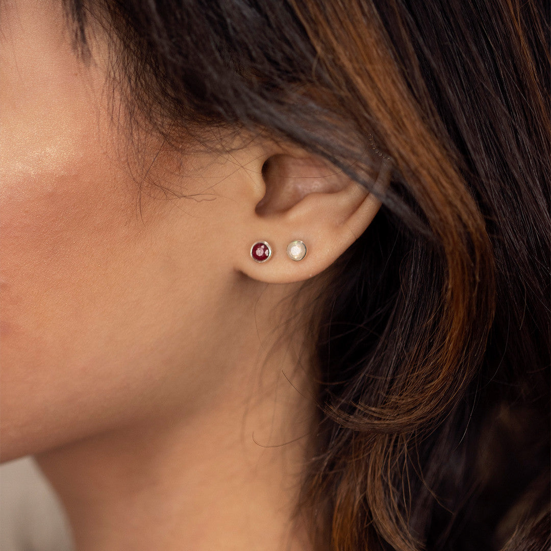 model wearing gold mini stud earrings with ruby gemstone