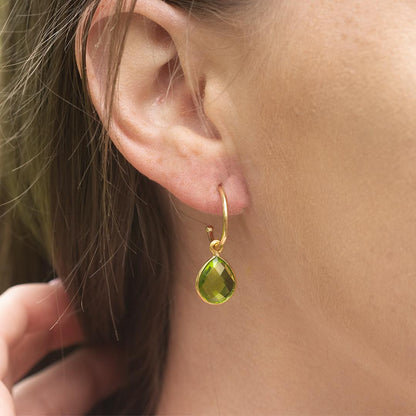 close up of model wearing peridot drop hoop earrings