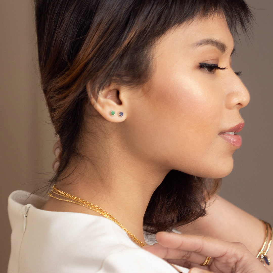 model wearing silver mini stud earrings with emerald gem stone