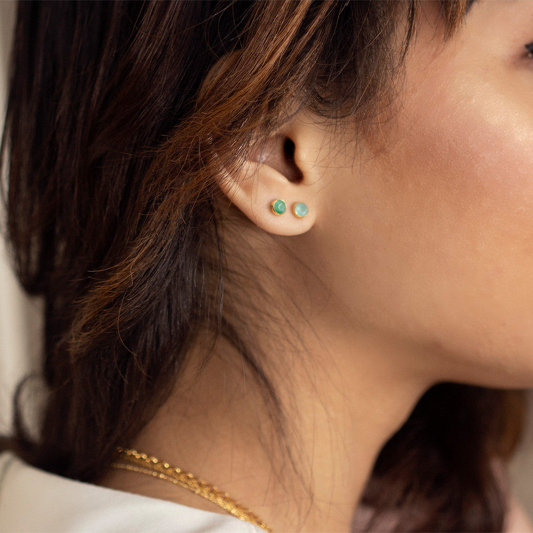 model wearing silver mini stud earrings with emerald gemstone