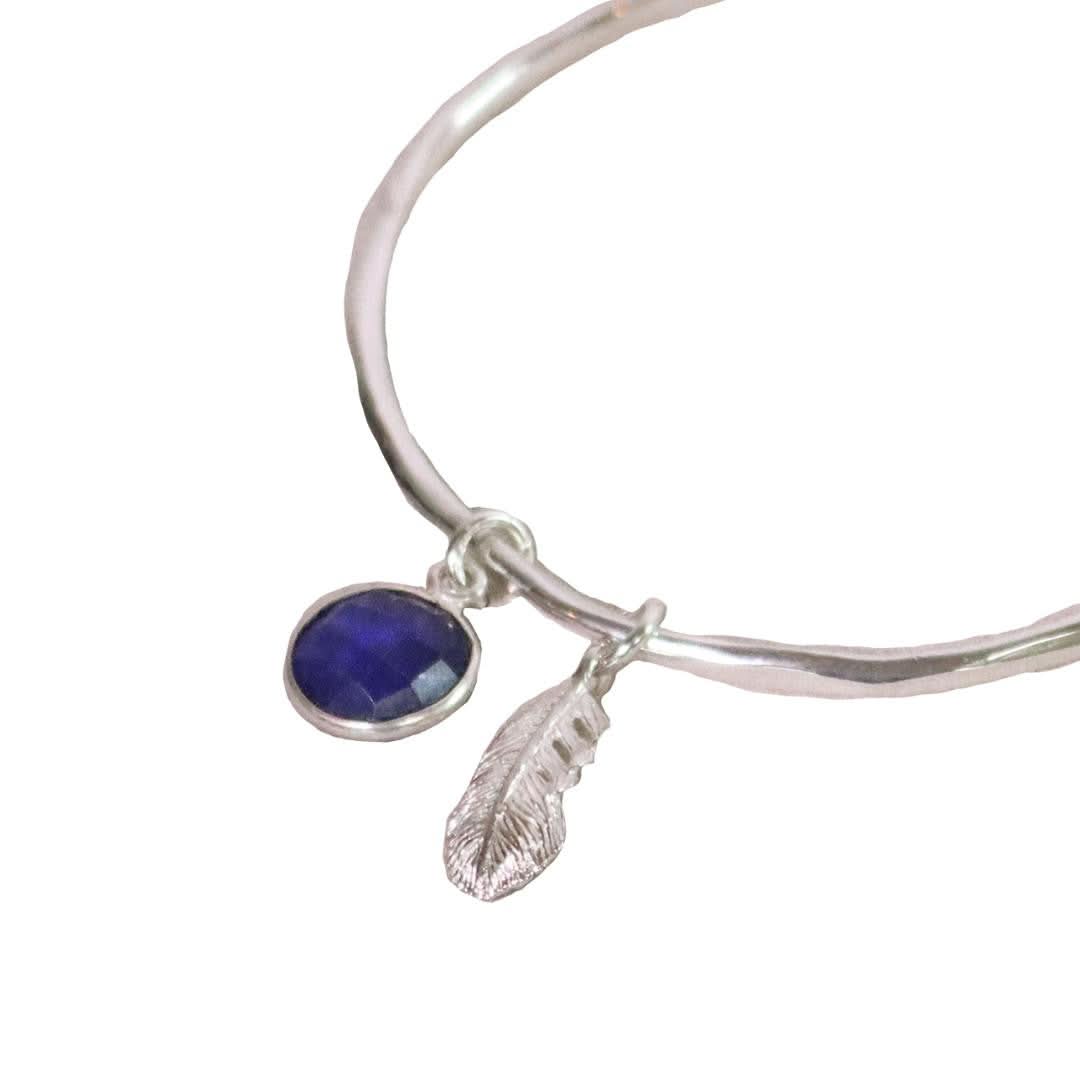 close up of Lily Blanche silver bangle with real sapphire and feather charm