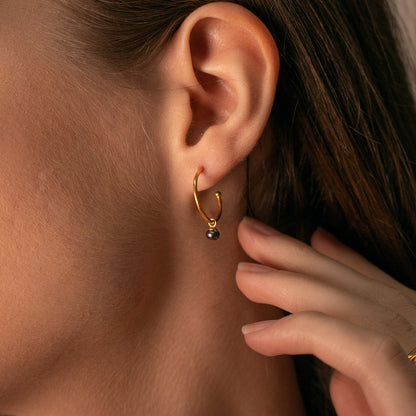 close up of model wearing dainty pearl drop hoop earrings 