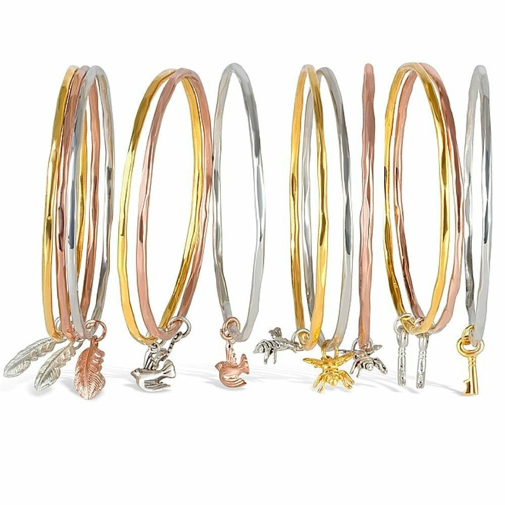 collection of charm bangles each with different charms on a white background 