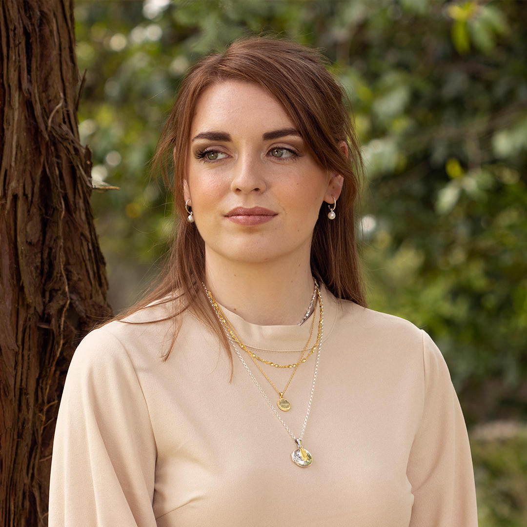 model wearing round locket in silver with other jewellery 