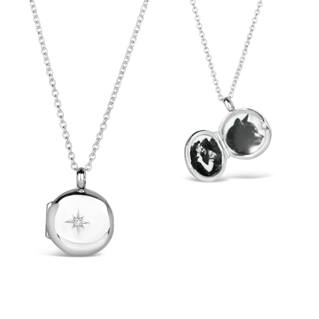 small round diamond locket in silver with opened and closed view on a white background