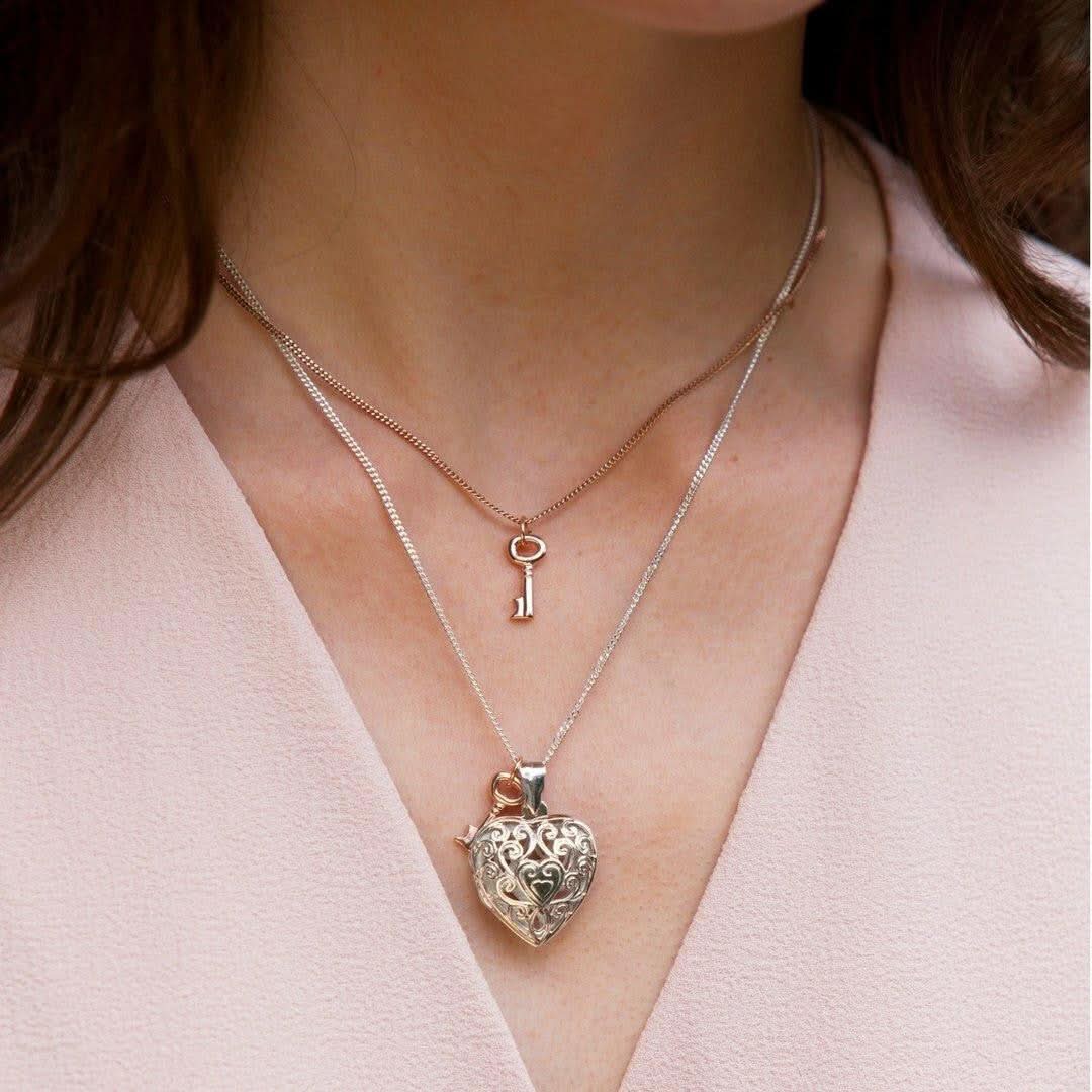 close up of model wearing key pendant along with key locket 