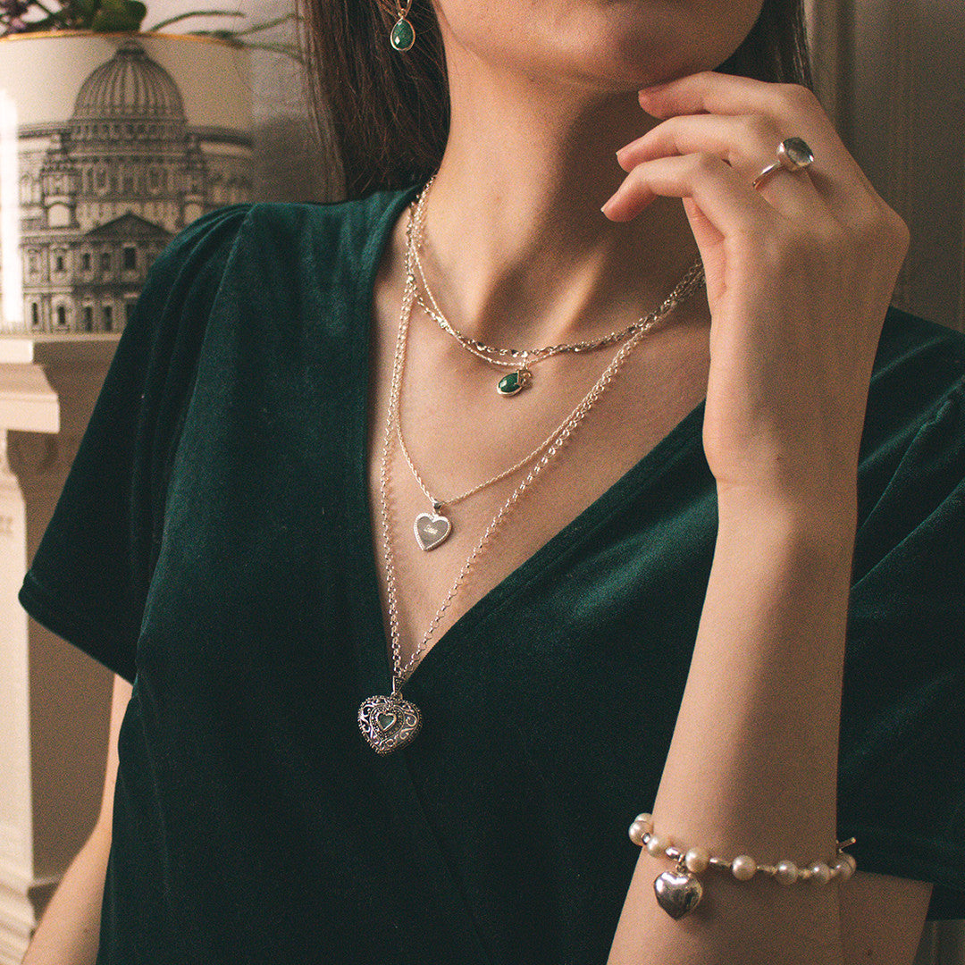 model wearing emerald vintage heart locket in silver with other jewellery