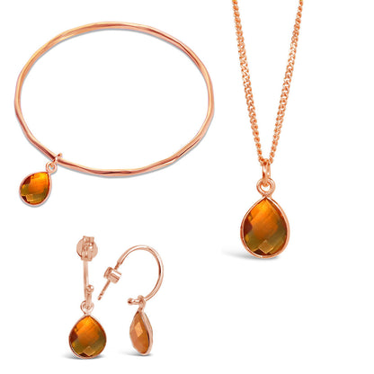 rose gold citrine charm bangle, necklace and drop hoop earrings on a white background