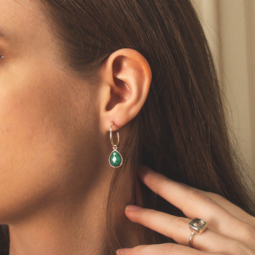 closeup of model wearing emerald drop hoop earrings in silver