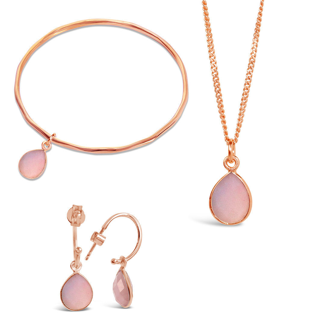 rose gold pink opal charm bangle, necklace and drop hoop earrings on a white background