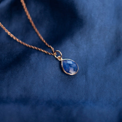 rose gold sapphire charm necklace on a blue background