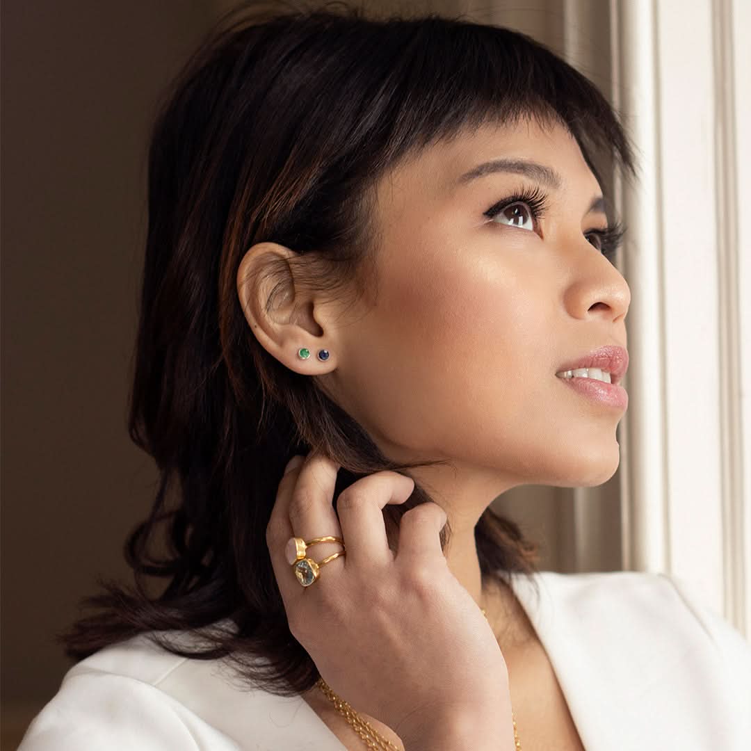 Model wearing sapphire mini stud earrings in silver facing sideways