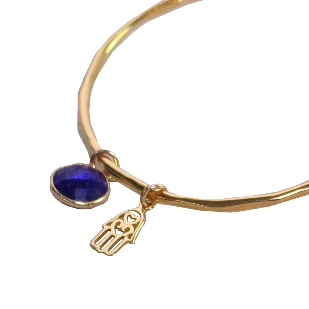 close up of sapphire charm bangle in gold with hamsa hands symbol