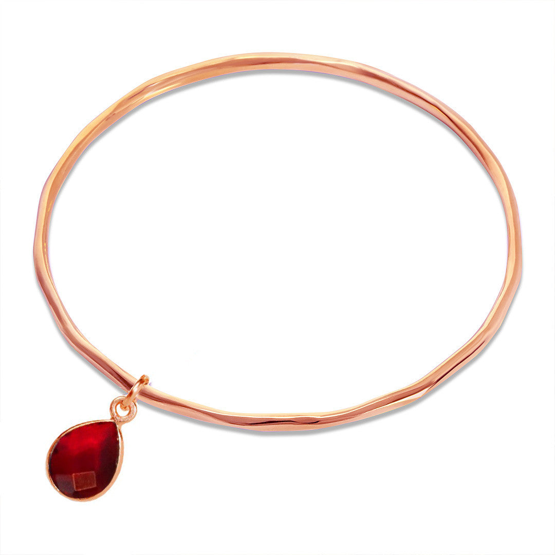 garnet charm bangle in rose gold on a white background