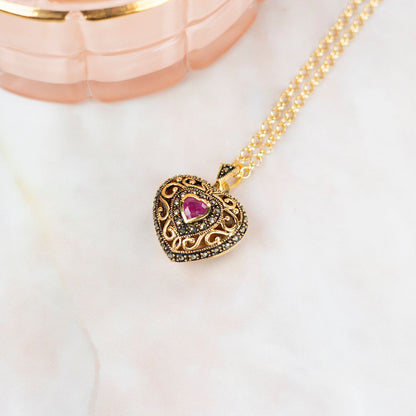 ruby vintage heart locket in gold on a white background