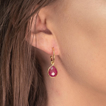 closeup of model wearing ruby drop hoop earrings in gold