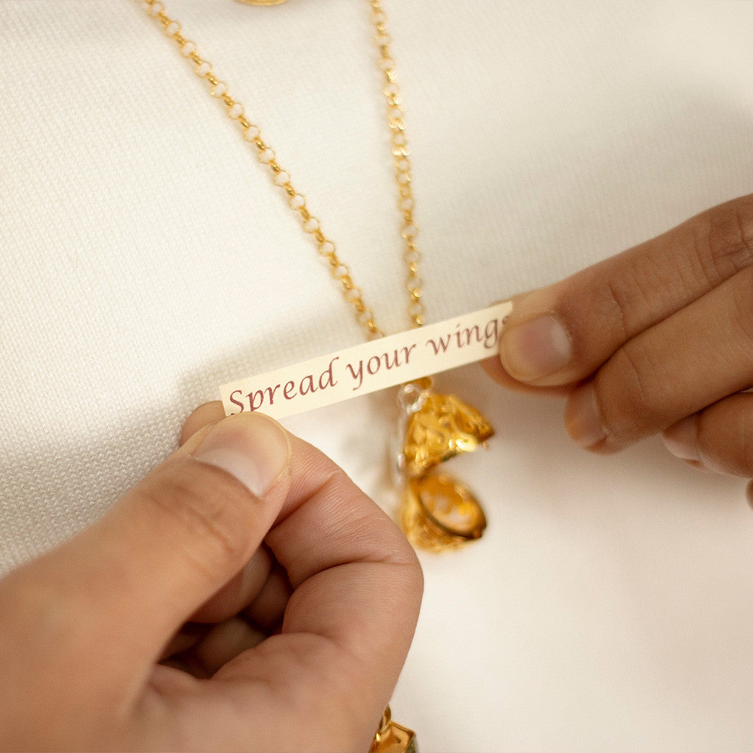 model wearing gold bird locket and holding bespoke message