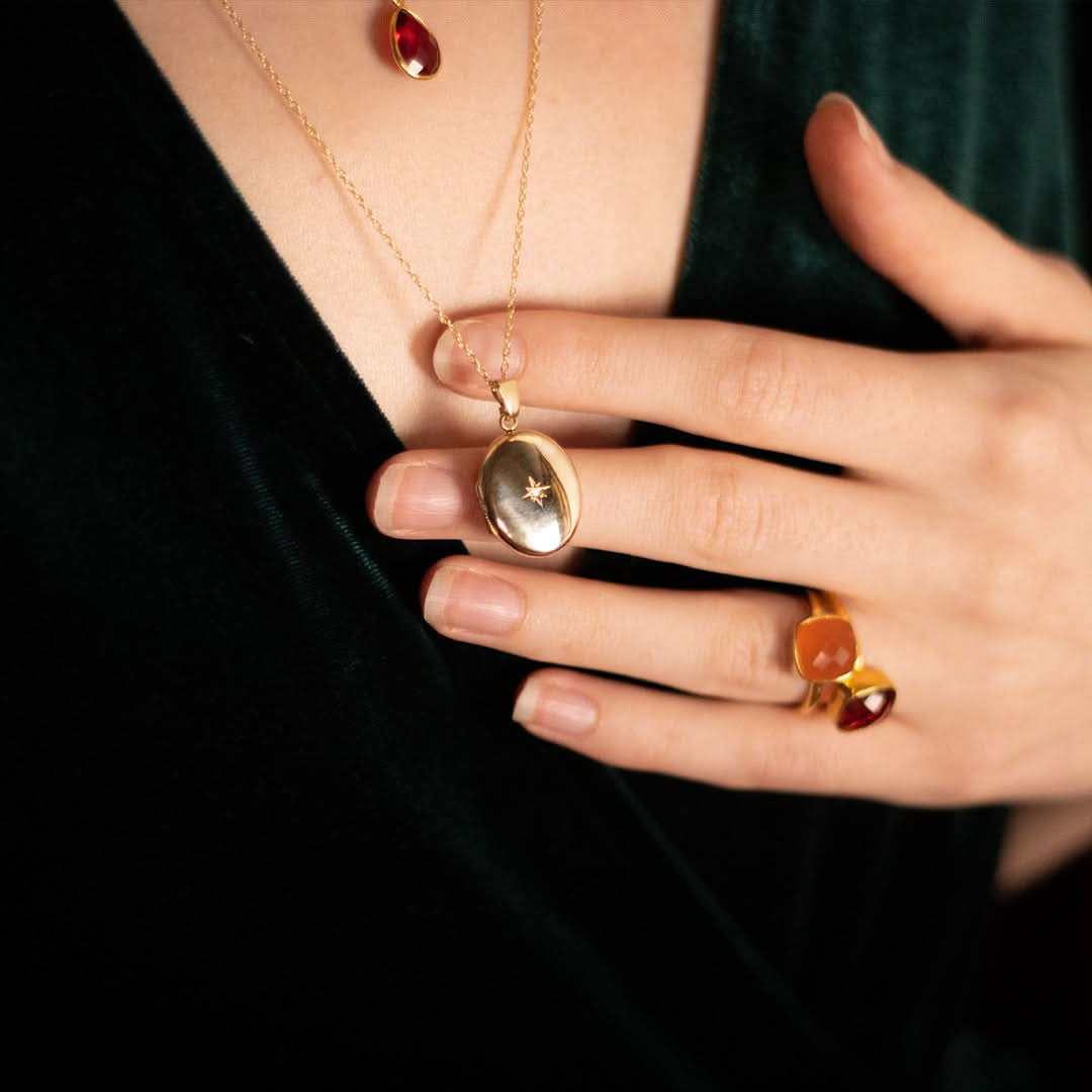 closeup of model wearing diamond oval locket in gold