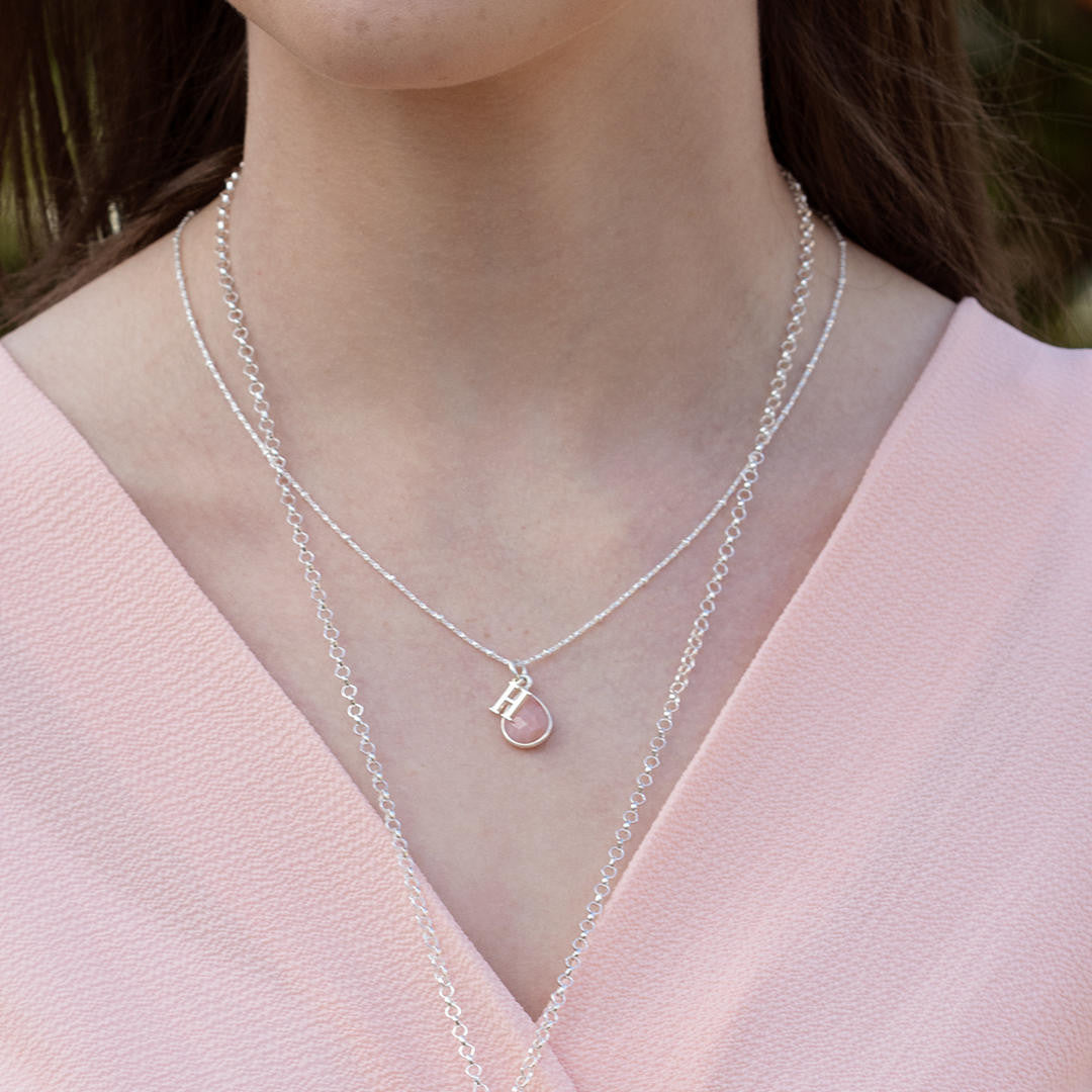 model wearing white gold beaded chain with silver birthstone and initial