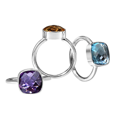 Trio of silver cocktail rings in purple ametyst, blue topaz and citrine on white background