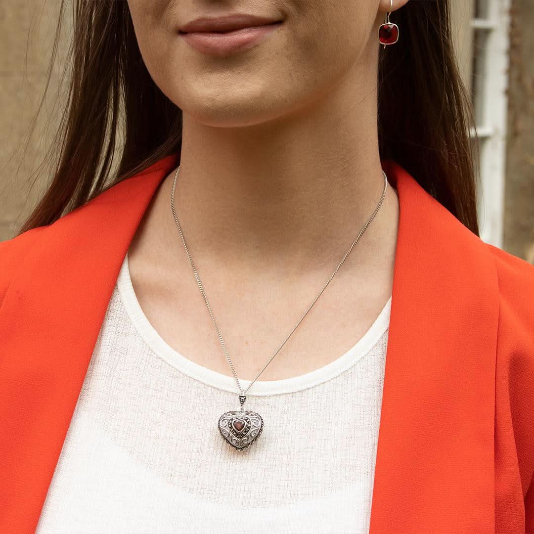 model in white top wearing white gold vintage heart locket with garnet gemstone