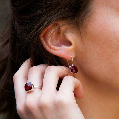 close up of model wearing garnet earrings and matching ring  