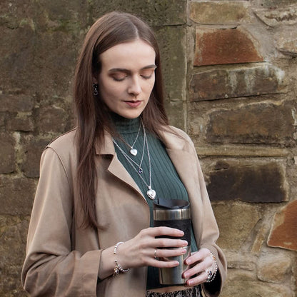 model holding cup wearing white gold heart shaped locket with moon charm