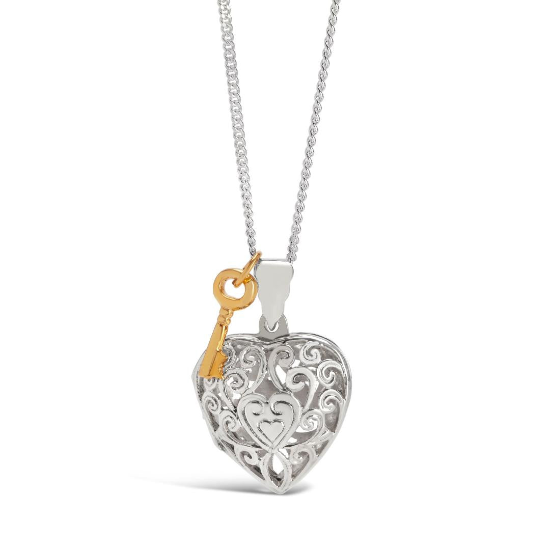 white gold key locket with gold charm attached on a white background